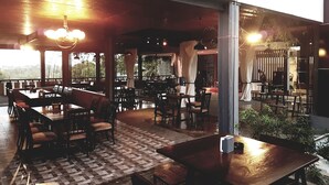 Un restaurant en plein air avec des tables et des chaises en bois, un sol à carreaux et une vue sur le paysage.