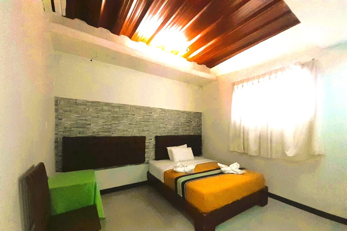 Una habitación de hotel con una cama, un escritorio y una silla.