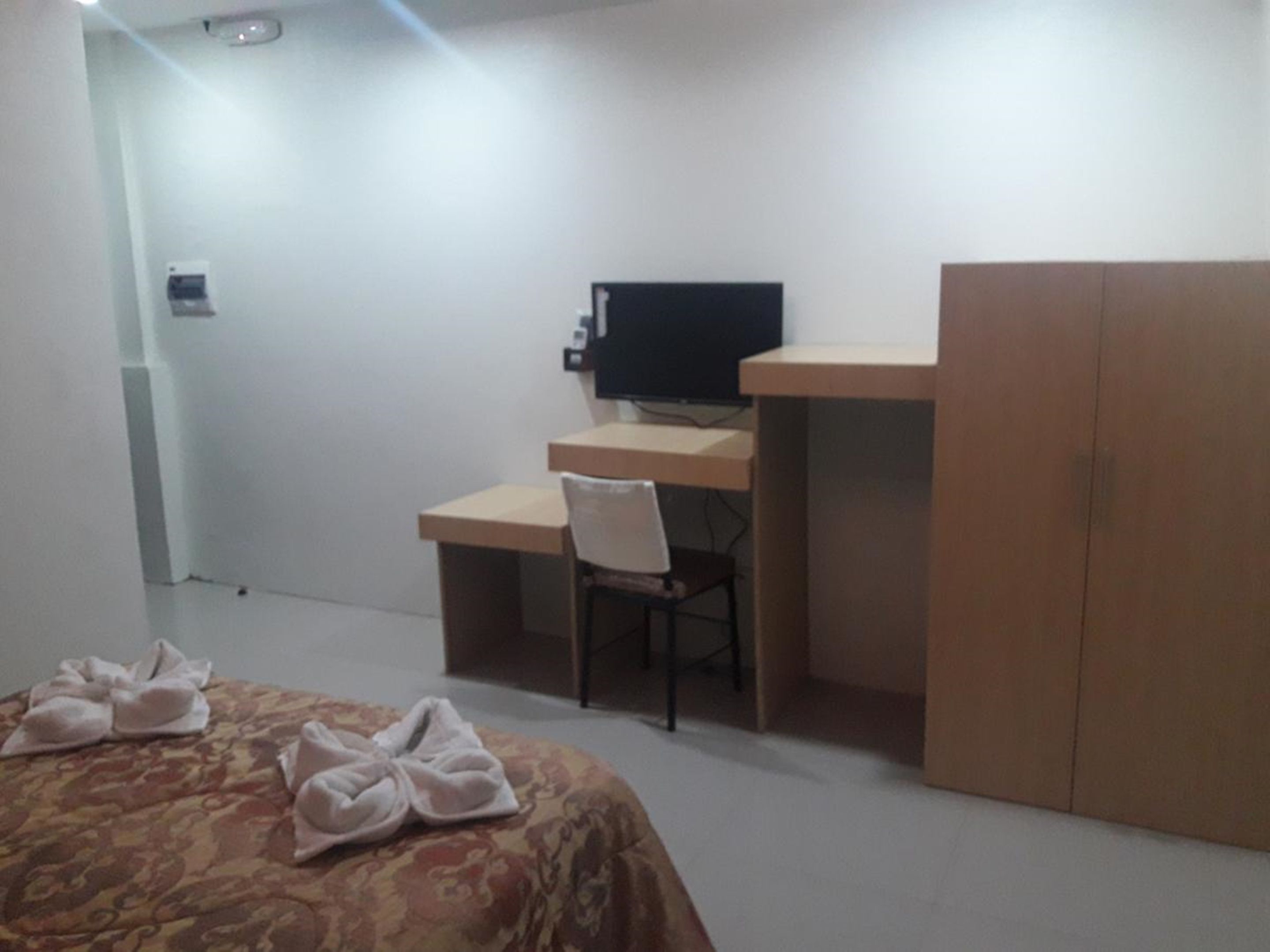 Een slaapkamer met een bed, een bureau, een stoel en een kledingkast.