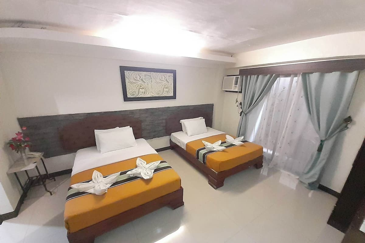 Habitación de hotel con dos camas, una obra de arte grande en la pared y una ventana con cortinas.