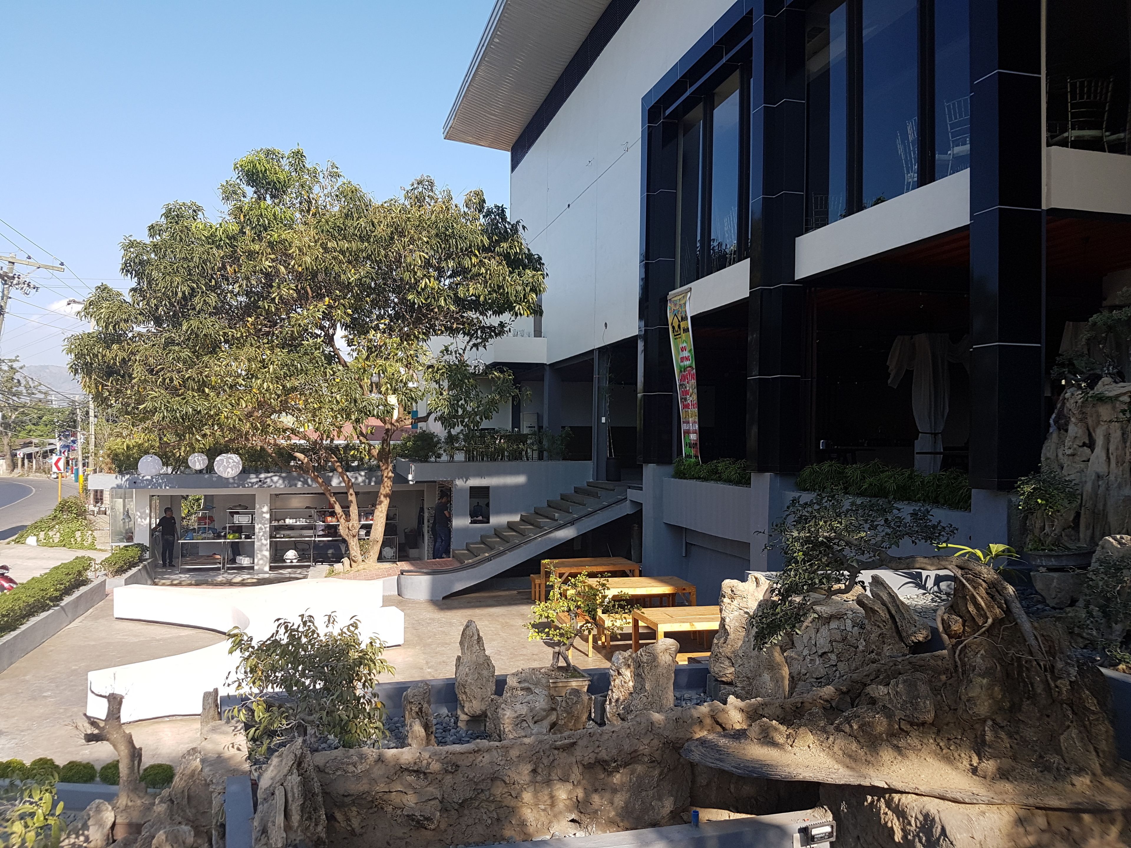 Un edificio moderno con un patio ajardinado que incluye un jardín de rocas, zonas de estar y un árbol.