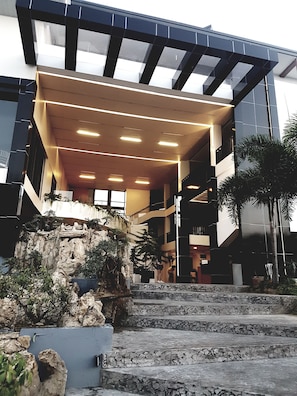 A modern building with a stone facade, a staircase leading to the entrance, and a covered area with lights. - MelSol Hotel (Bantay)
