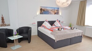 Una camera da letto moderna con un letto, un tavolino, una sedia e un quadro appeso al muro.