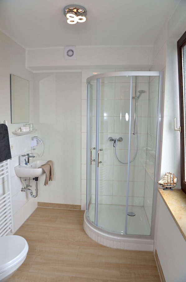 Un baño moderno con cabina de ducha de vidrio, un lavabo con toalla y un espejo.