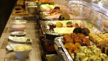 Buffet amb diferents plats, incloent carns, formatges i fruita.