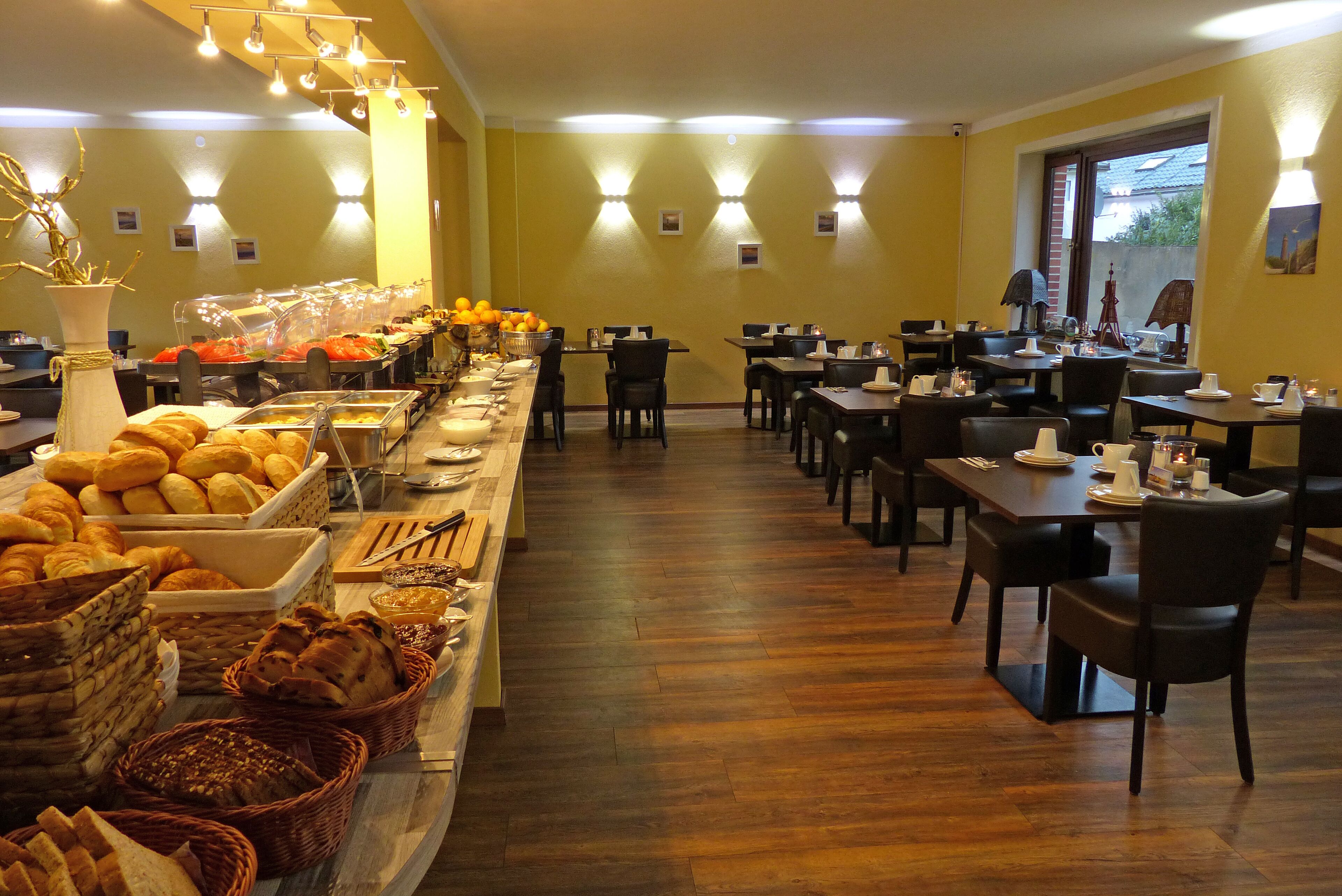 Un espace buffet proposant divers plats et une zone réservée aux repas, avec des tables et des chaises.