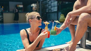 A poolside setting with a person holding a drink.