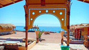 A beachside walkway leading to a covered area with a view of the sea. - Sahara Beach Camp (Nuweiba)