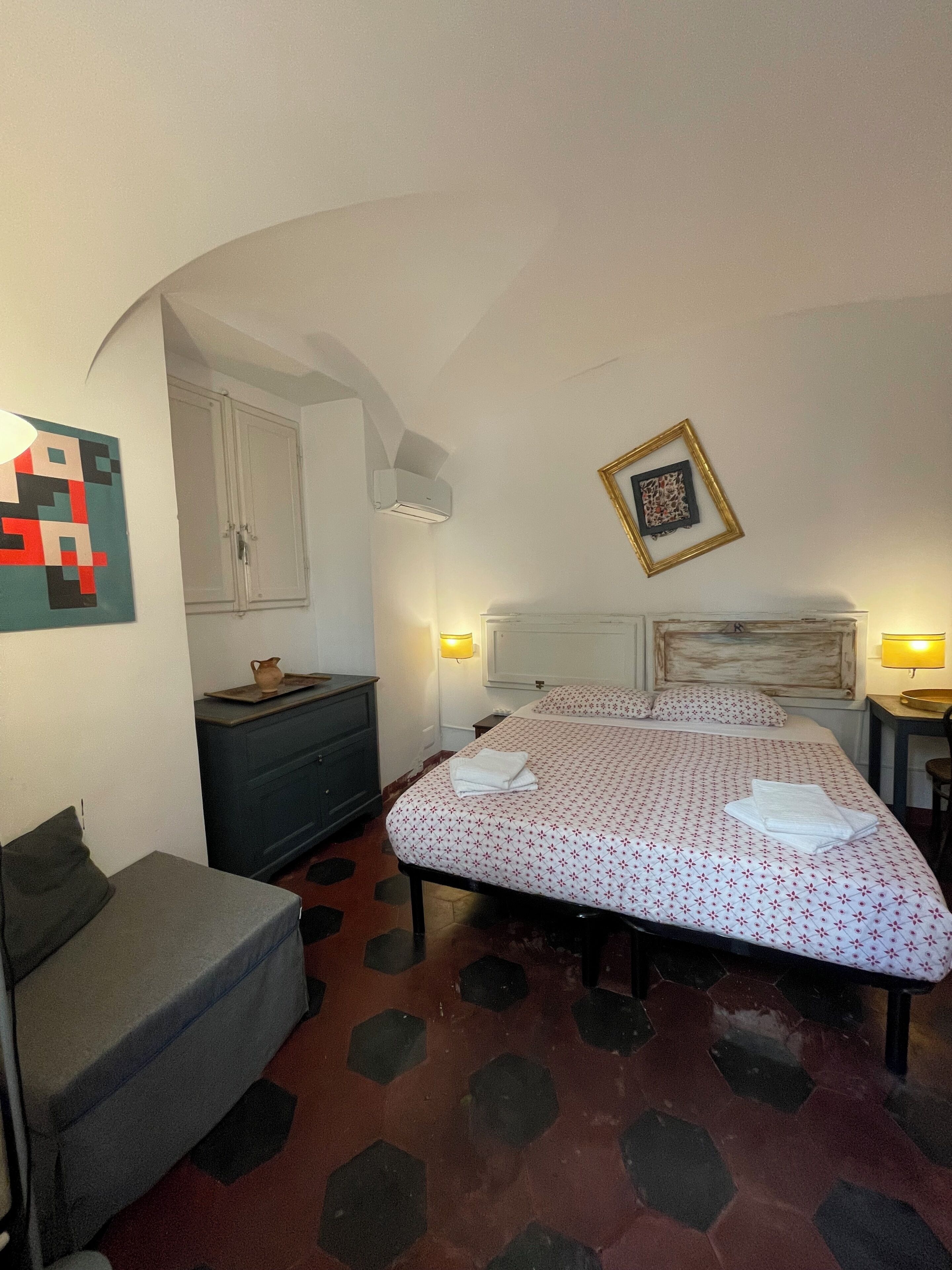 A bedroom with a bed, a desk, a chair, a wardrobe, and a unique hexagonal floor pattern.