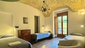 A room with two beds, a wooden wardrobe, a chandelier, and a large window. - Il Plancton (Rome)