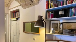 A room with a bookshelf, a desk, a lamp, and a round table. - Il Plancton (Rome)