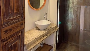 A bathroom with a wooden vanity, a round mirror, a white sink, and a glass shower enclosure. - Il Plancton (Rome)