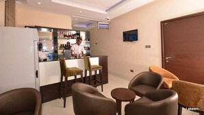 Una sala de estar moderna con una zona de bar, sofás de cuero y un televisor montado en la pared.