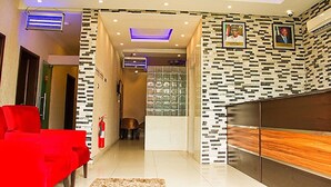 Una sala de estar moderna con un sofá rojo, un mueble de madera y una pared con estampado.