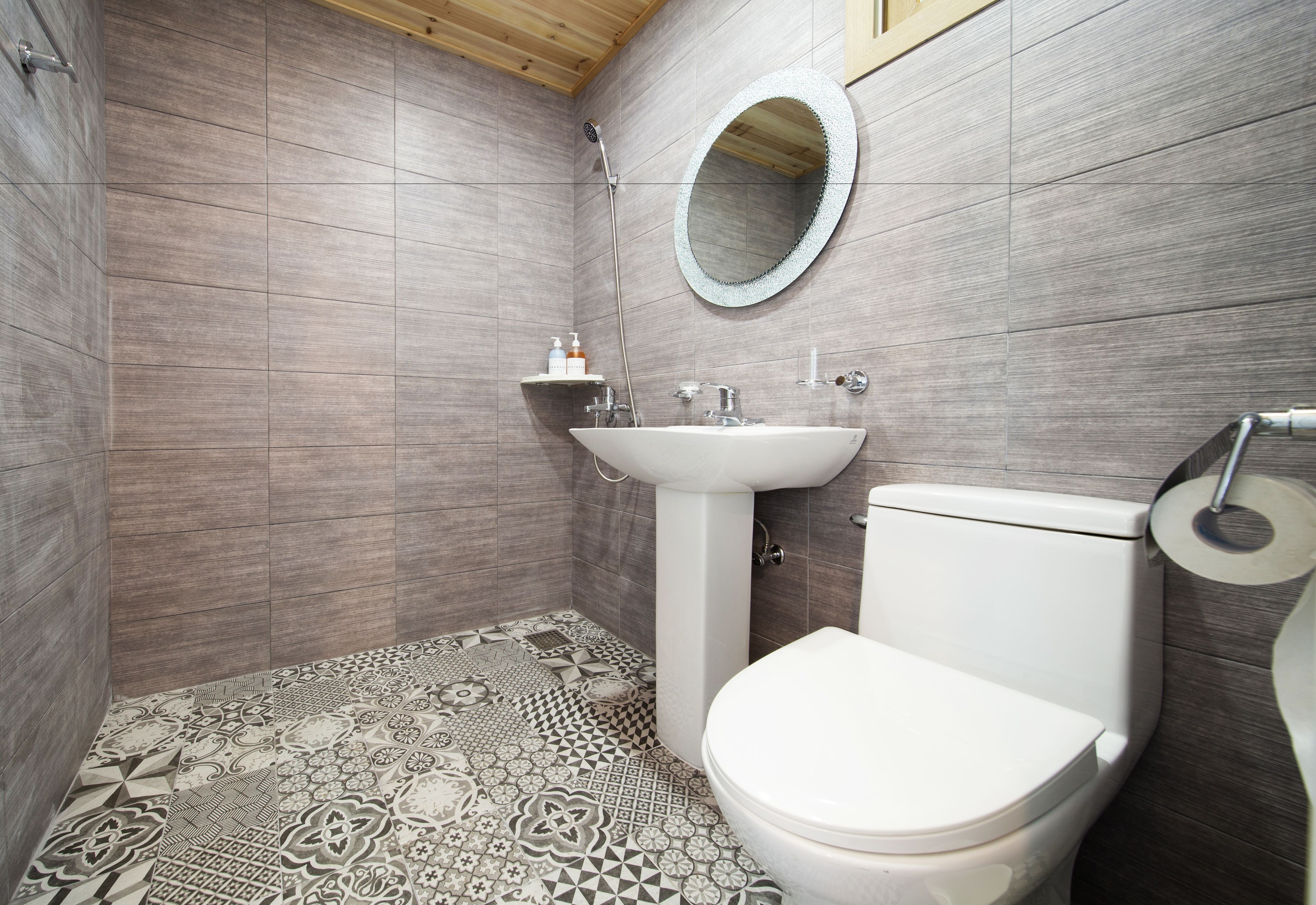 A bathroom with a patterned floor, a white sink, a toilet, and a mirror.