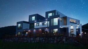 A modern hotel with a 'POETA' sign, featuring a stone facade, multiple windows, and a wooden deck. - Poeta Pension (Seogwipo)