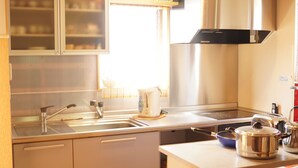 Une cuisine moderne équipée d’appareils électroménagers en acier inoxydable, d’un évier à deux bacs et d’une fenêtre avec des stores.