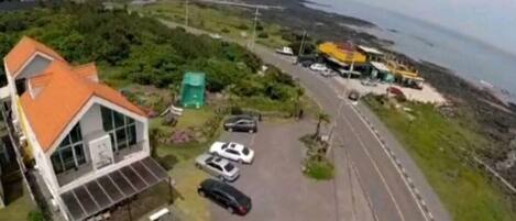 Una propiedad costera con zona de estacionamiento, un edificio de techo rojo y vista al mar.