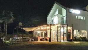 Un bâtiment moderne à deux étages, doté d’une façade en verre, d’un balcon et d’un hall d’entrée bien éclairé.