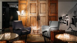 A room with wooden doors, two armchairs, a small table, and a wall with artwork. - Ruby Coco Hotel Dusseldorf by IHG (Düsseldorf)