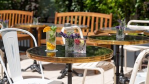 Outdoor seating with round tables and white chairs, some with drinks and flowers. - Ruby Coco Hotel Dusseldorf by IHG (Düsseldorf)
