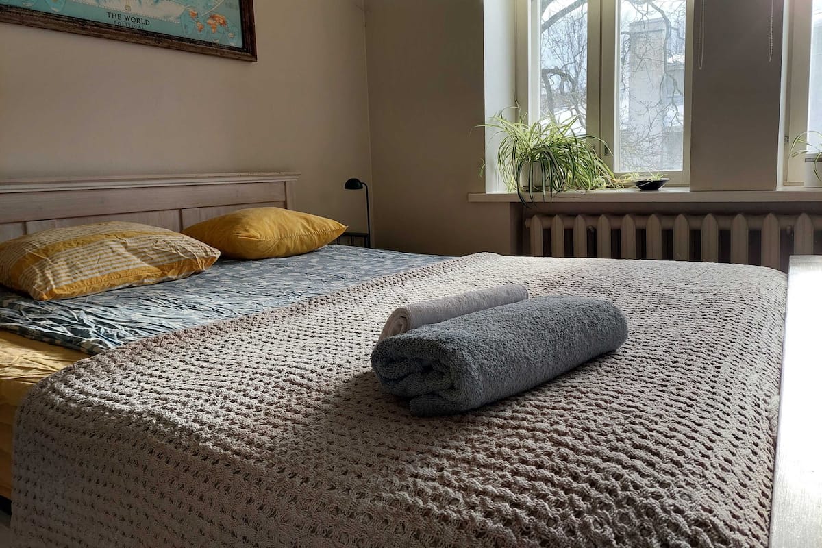 A bedroom with a bed, a window with a view, and a world map on the wall.