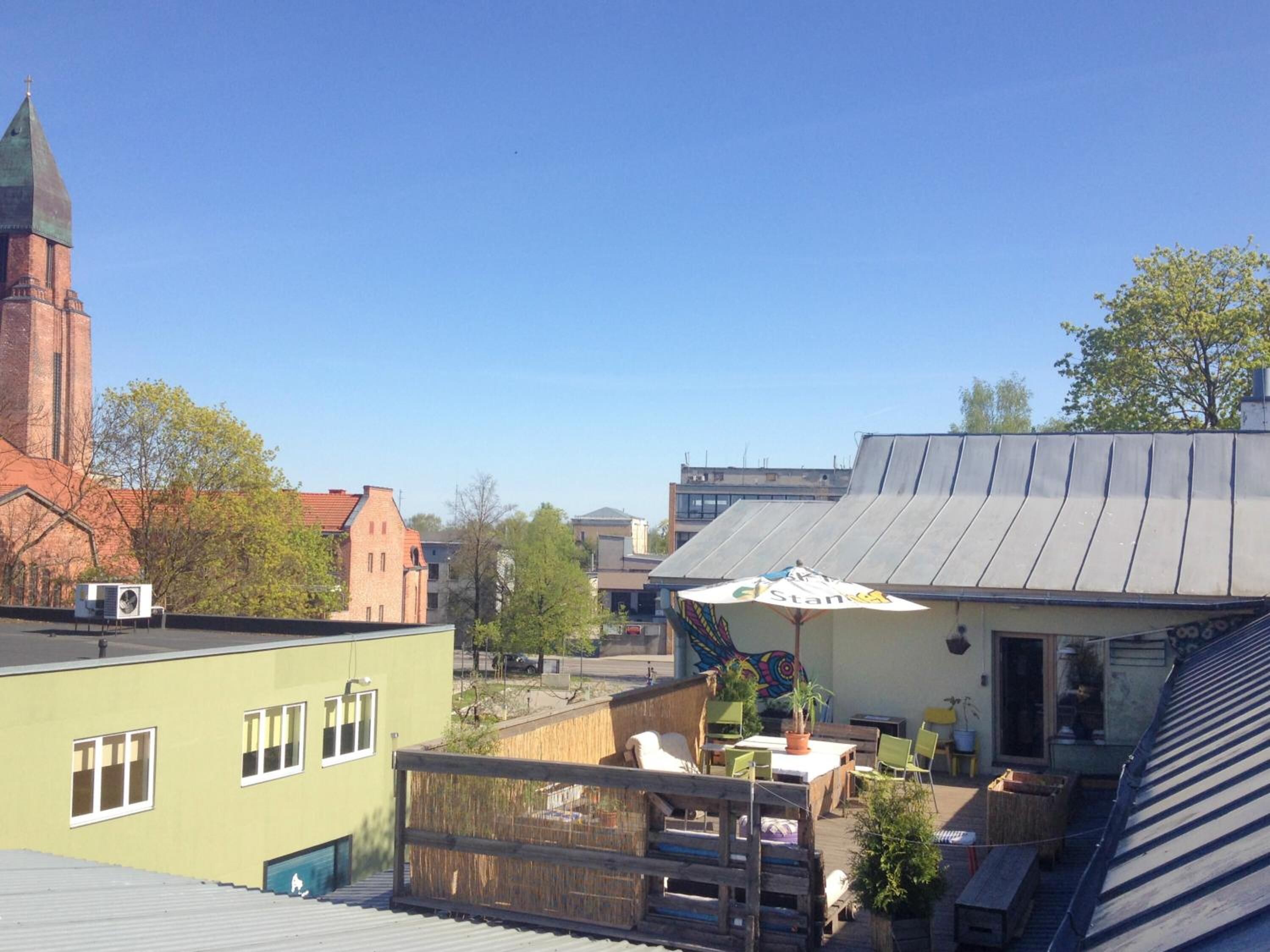 Terraço no telhado com área de estar ao ar livre, uma igreja ao fundo e um edifício com cobertura de metal.