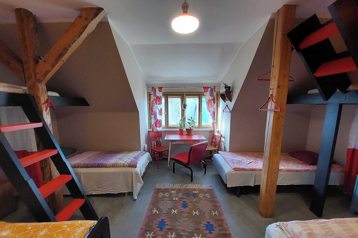 A dormitory room with bunk beds, a desk, and a chair.