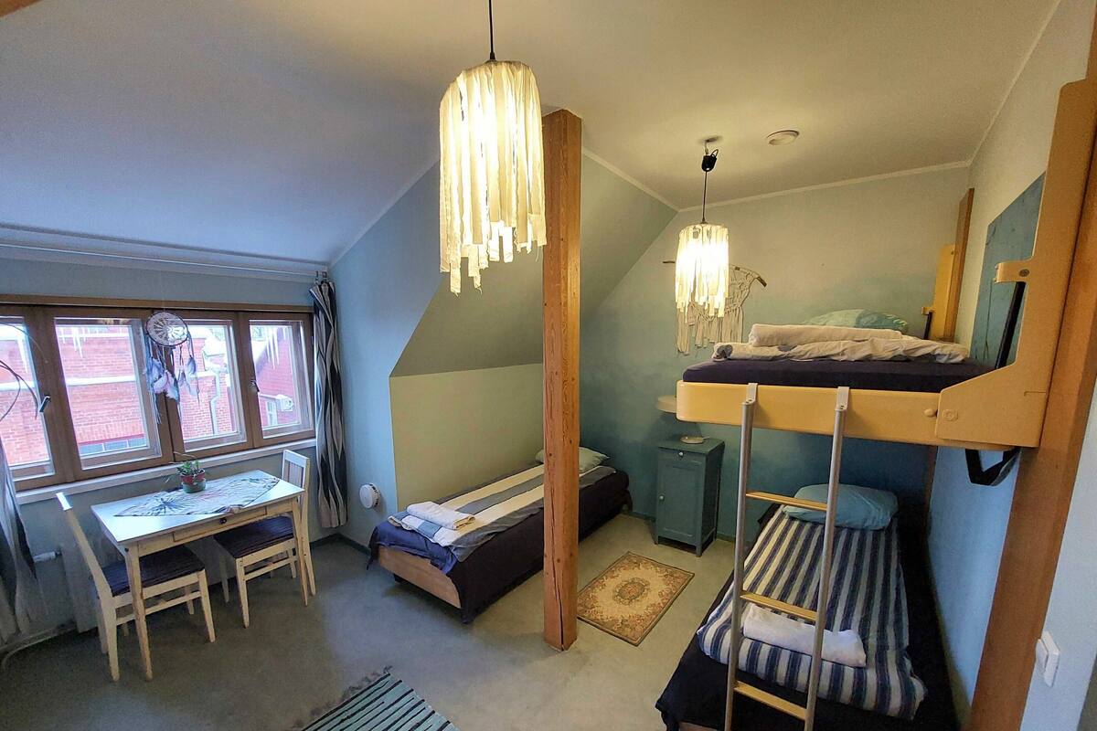 A dormitory room with bunk beds, a desk, and a window with curtains.