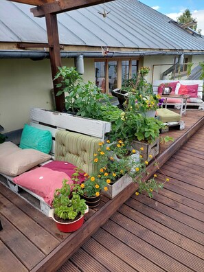 A wooden deck with a bench, potted plants, and a small table. - Looming Hostel (Tartu)
