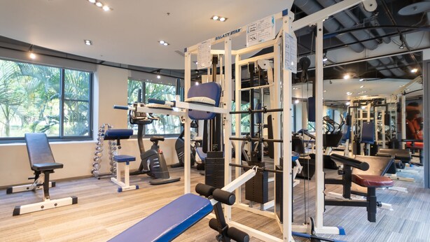 Un gimnasio con diversos equipos de ejercicio, como una estructura para sentadillas, bancos y pesas.