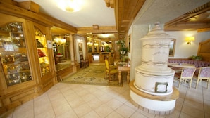 A hotel lobby with wooden paneling, a central fountain, and a reception desk. - Alpen Hotel Vidi (Pinzolo)