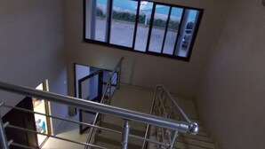 Una scala con corrimano in metallo, vista su un parcheggio attraverso una finestra e una porta che dà su un'altra stanza.