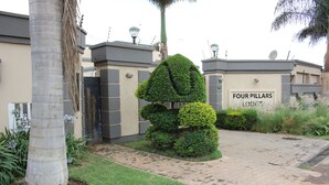 Un cancello con un cartello che riporta la scritta "FOUR PILLARS LODGE".