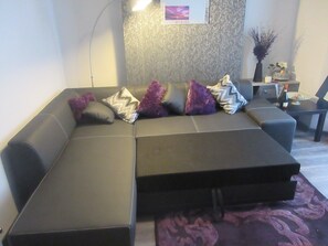 A modern living room with a sectional sofa, a small side table, and a decorative wall.