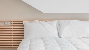A bedroom with a slatted headboard, white bedding, and a visible light switch. - B&B Jonio Roma (Rome)
