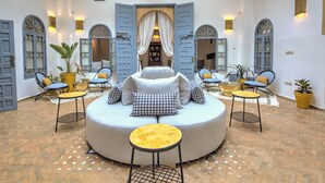 A circular seating area with a sofa and chairs, surrounded by potted plants and a patterned floor. - Riad Amaris (Rabat)
