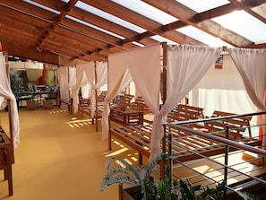A room with wooden benches and white canopies, a tiled floor, and a wooden ceiling with skylights. - Tatralandia Chatky 109 a 110 (Liptovsky Mikulas)