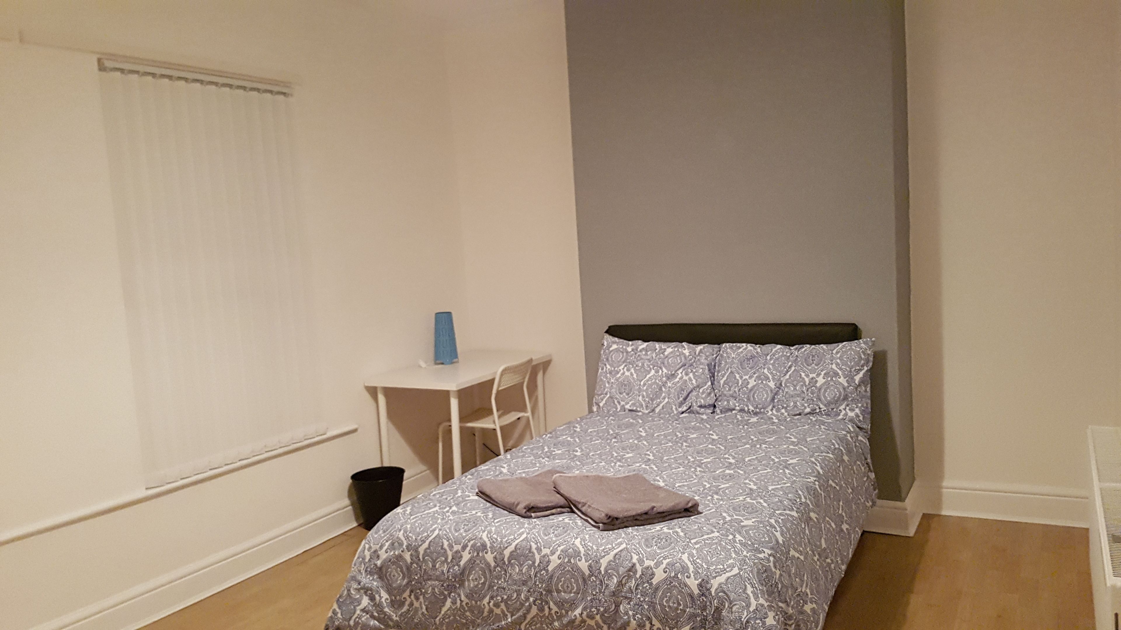 Un dormitorio con una cama, un escritorio pequeño y una silla.