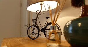 A bicycle lamp on a wooden table with a clear glass vase containing reed sticks. - Superb central House (Liverpool)