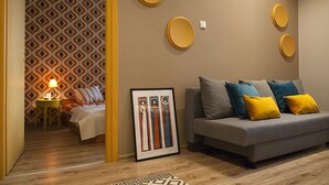 Un salon moderne avec un canapé gris, des coussins jaunes et un papier peint à motifs.