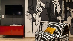 Une pièce avec un meuble rouge, un canapé à motifs noir et blanc et une grande fresque murale.