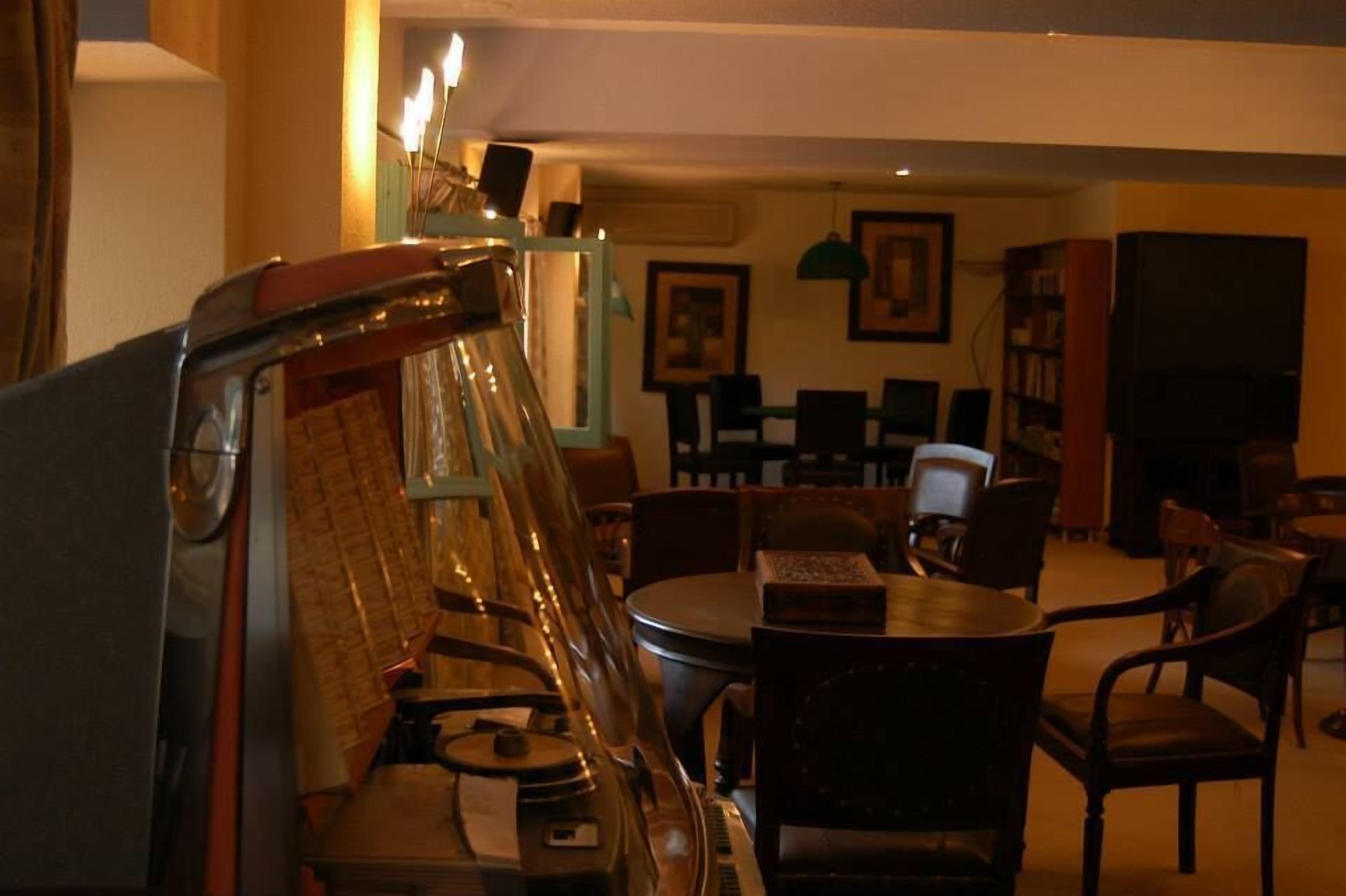 Una sala de estar acogedora con un piano, una mesa de comedor y sillas. Hay cuadros en la pared y una estantería.