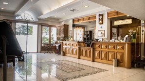 A reception area with a wooden reception desk, a clock, and a reception sign. - Aegeon (Samos)