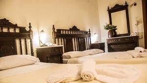 A hotel room with two beds, wooden headboards, a large mirror, and a nightstand with a lamp. - Aegeon (Samos)