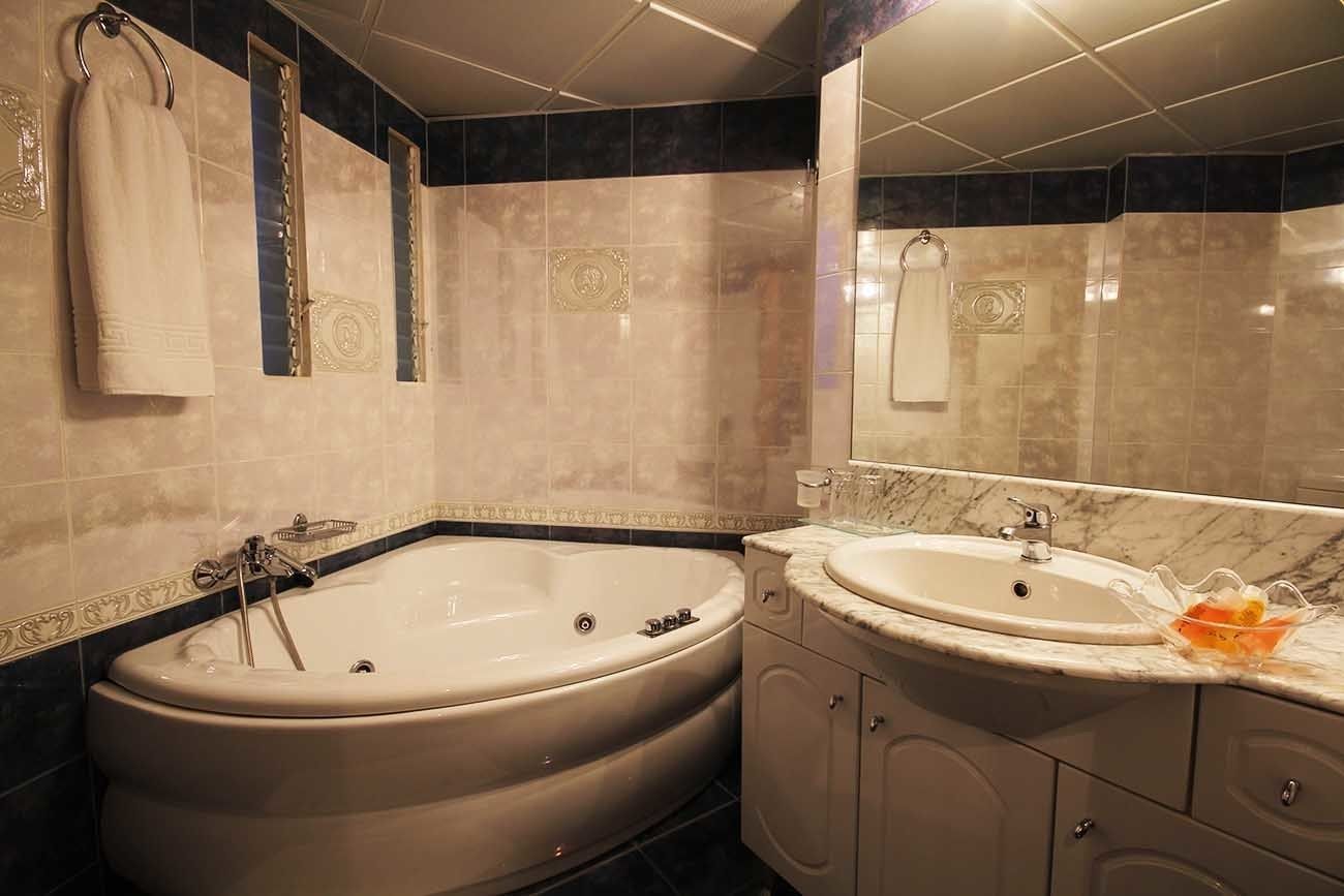 Une salle de bain avec une grande baignoire, un lavabo et un miroir.