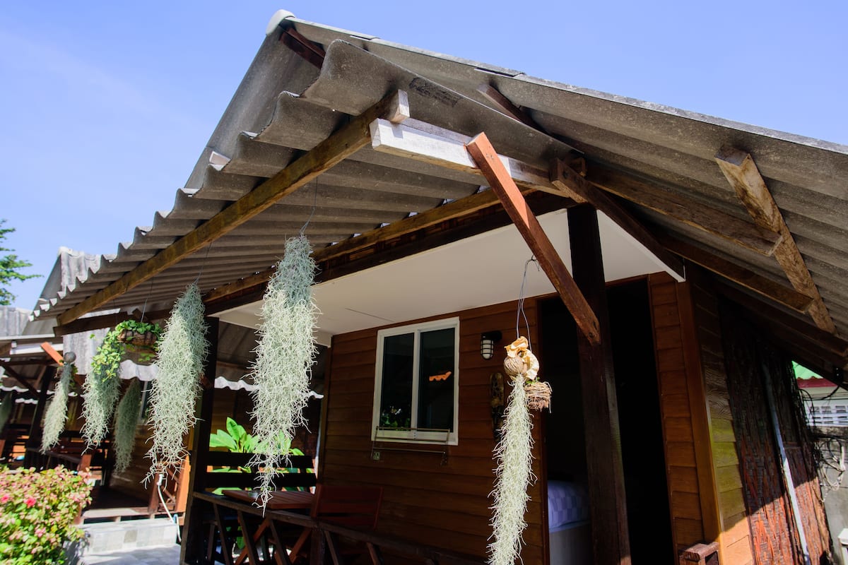 A wooden cabin with a sloped roof, a window, and hanging plants.