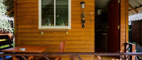 Una cabaña de madera con comedor, una ventana y una puerta identificada con