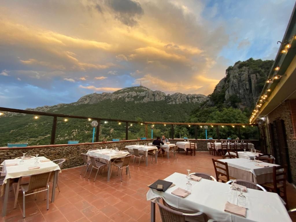 An outdoor dining area with tables set for guests, overlooking a mountainous landscape.