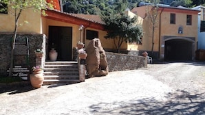 A rustic building with a stone facade, a wooden door, and steps leading to the entrance. There are potted plants and a large vase near the door. - Hotel Sant'Elene (Dorgali)